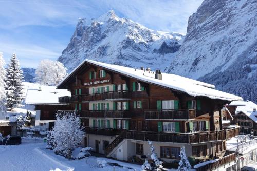 a snow covered building with a mountain in the background at Hotel Gletschergarten in Grindelwald