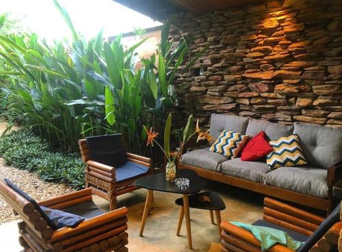 a patio with a couch and chairs and a stone wall at Casa jardim com ofurô - Chapada dos veadeiros in Cavalcante