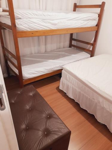 two bunk beds in a room with a wooden floor at Lindo Flat em Maresias in São Sebastião