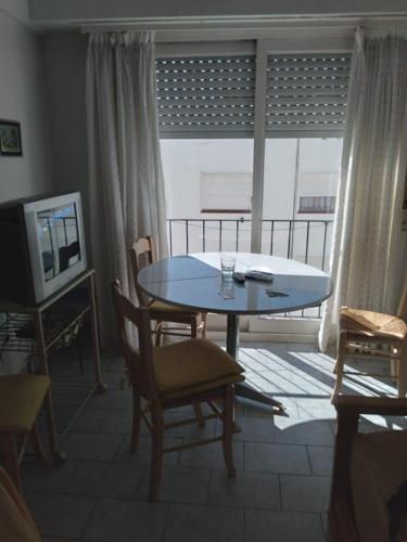 sala de estar con mesa, sillas y TV en Departamento sobre avenida Colón en Mar del Plata