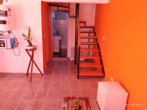 pasillo con escalera en una habitación con paredes de color naranja en Mí cielo en Huerta Grande