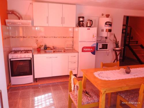 cocina con electrodomésticos blancos y mesa de madera en Mí cielo en Huerta Grande