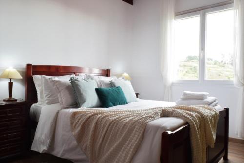 a bedroom with a bed with white sheets and a window at Casa da Piedade, a Home in Madeira in Ponta do Sol