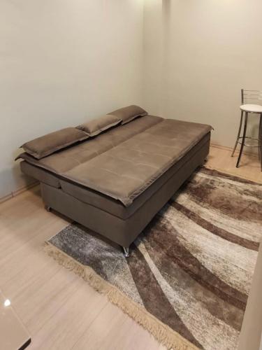uma cama sentada num tapete num quarto em Aconchego Poços de Caldas em Poços de Caldas