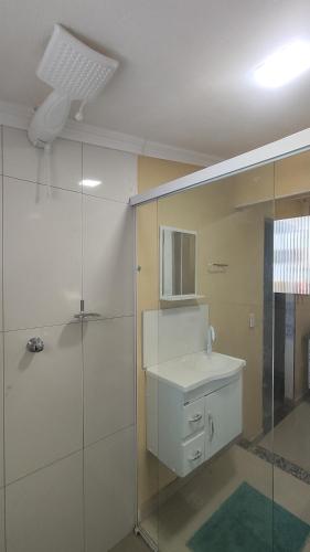 a bathroom with a sink and a glass shower at Angel Hospedagem de quartos Self Check in in Vila Velha