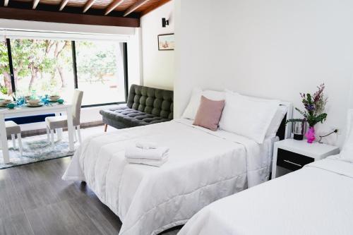 a white bedroom with two beds and a couch at Hotel Casa Luna in Cúcuta