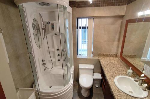 a bathroom with a shower and a toilet and a sink at Amplio departamento, sector parque LA CAROLINA in Quito