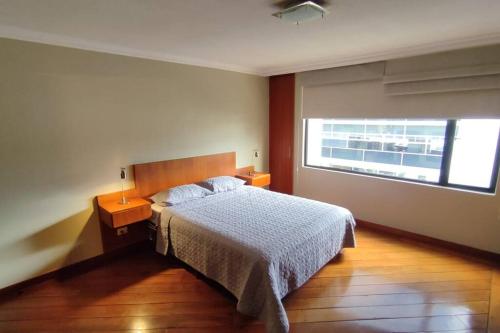 a bedroom with a bed and a window at Amplio departamento, sector parque LA CAROLINA in Quito