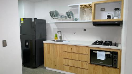 a kitchen with a black refrigerator and a sink at Edificio Helena in Medellín