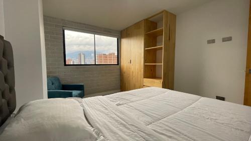 a bedroom with a bed and a window and a chair at Edificio Helena in Medellín