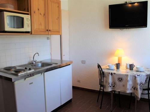 a kitchen with a table and a sink and a microwave at Appartement Vars, 1 pièce, 2 personnes - FR-1-330B-111 in Vars