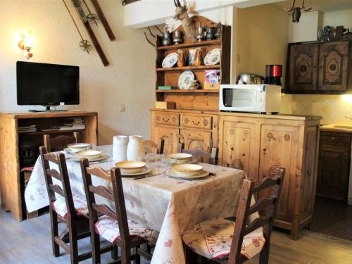 une cuisine avec une table avec des chaises et un micro-ondes dans l'établissement Duplex charmant à Vars Les Claux, 6 couchages, proche pistes et commerces - FR-1-330B-108, à Vars