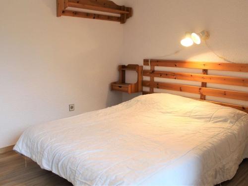 Schlafzimmer mit einem weißen Bett mit einem Kopfteil aus Holz in der Unterkunft Appartement Vars, 3 pièces, 8 personnes - FR-1-330B-125 in Vars