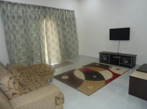 uma sala de estar com um sofá e uma televisão de ecrã plano em Pertama Homestay em Kangar
