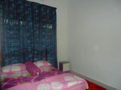 um quarto com uma cama rosa e uma cortina azul em Pertama Homestay em Kangar