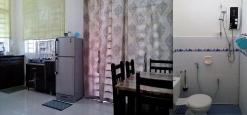 uma cozinha com uma mesa e um frigorífico em Pertama Homestay em Kangar