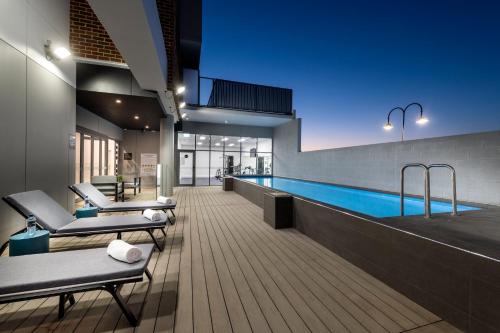 a swimming pool in a building with two lounge chairs at Quest Midland in Midland Junction