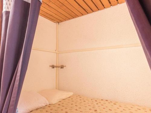 Cette chambre comprend un lit avec un rideau et une croix. dans l'établissement Studio chaleureux avec balcon à Serre-Chevalier, parking et casier à ski – 4 personnes - FR-1-330E-3, à Saint-Chaffrey