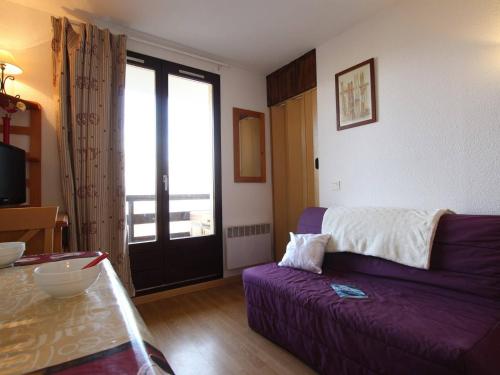 een woonkamer met een paarse bank en een raam bij Appartement Puy-Saint-Vincent, 1 pièce, 4 personnes - FR-1-330G-51 in Puy-Saint-Vincent