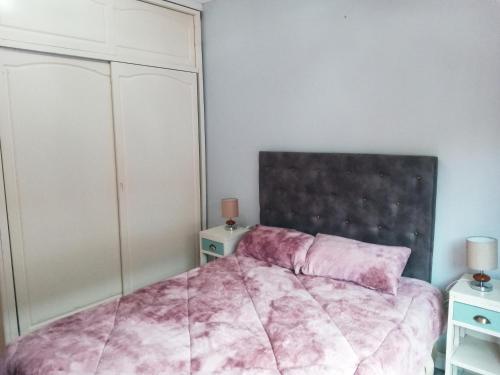 um quarto com uma cama cor-de-rosa com duas mesas-de-cabeceira em Depto Roca em Tres Arroyos