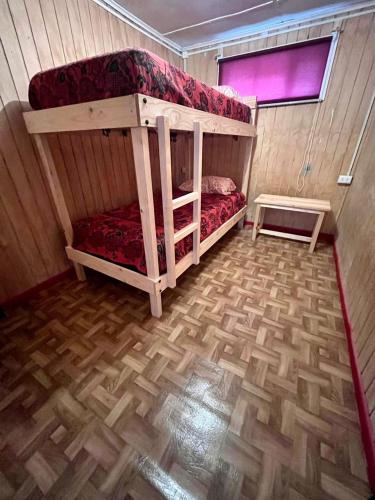 a small room with a bunk bed and a wooden floor at Isla yu Patagonia house in Puerto Natales