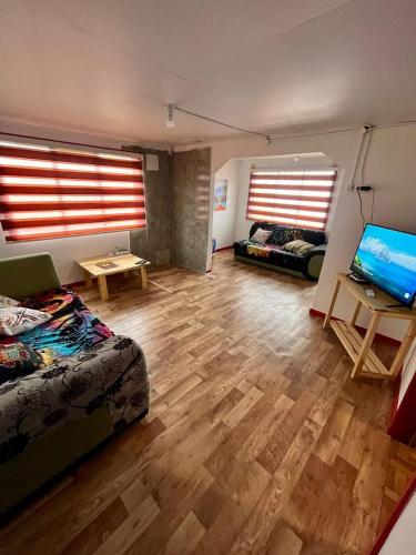 a living room with two beds and a flat screen tv at Isla yu Patagonia house in Puerto Natales