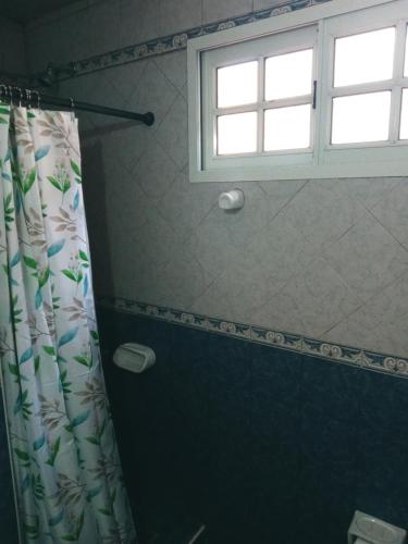 uma casa de banho com uma cortina de chuveiro e uma janela em Depto Roca em Tres Arroyos