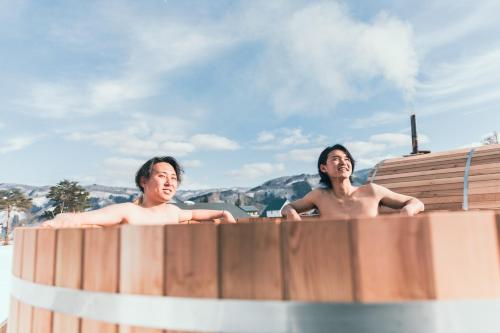 two men sitting in a bath tub with their backs turned at From P in Hakuba