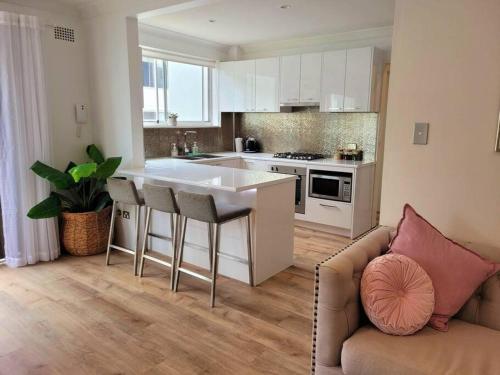 a living room with a couch and a kitchen at Ocean Front Apartment in Cronulla