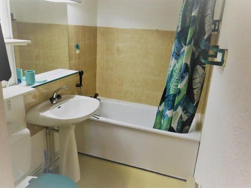 La salle de bains est pourvue d'un lavabo, d'une baignoire et d'un rideau de douche. dans l'établissement Duplex cosy 33m² à Arêches-Beaufort, pour 4 pers., pied des pistes, animaux admis, parking - FR-1-342-157, à Beaufort