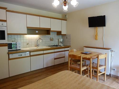 une cuisine avec des armoires blanches et une table en bois dans l'établissement Appartement cosy 4 pers, skis aux pieds, balcon, parking, 2 étoiles - Location dim. à dim. en hiver - FR-1-342-191, à Arêches