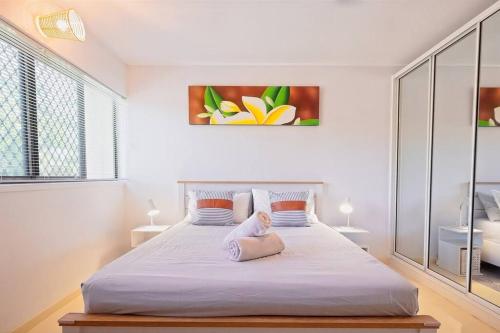 a white bedroom with a large bed in a room at Entertainer on Martyn in Cairns