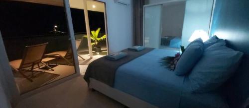 a bedroom with a large bed and a balcony at FENUA ORA in Mahina