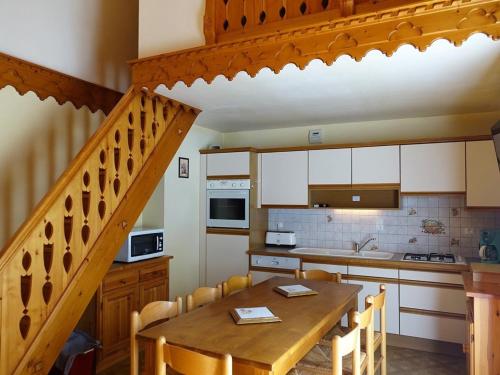 une cuisine avec une table en bois et un escalier en bois dans l'établissement Duplex 2** pour 8 pers. au pied des pistes avec balcon, parking et équipements familials - FR-1-342-149, à Arêches