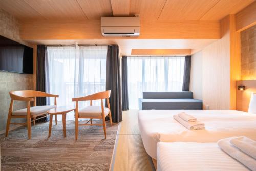ein Hotelzimmer mit 2 Betten, einem Tisch und Stühlen in der Unterkunft WELLSTAY Shinsekai Wakyo in Osaka