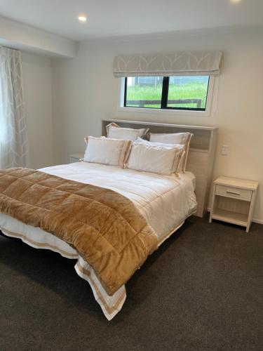 a bedroom with a large bed with a window at Tavis Burn Cottage on Maungatautari Mountain in Karapiro