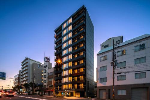 a tall building on a city street at dusk at WELLSTAY Shinsekai Wakyo in Osaka