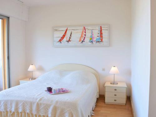 a bedroom with a white bed and a picture of surfboards at Appartement Le Lavandou, 2 pièces, 4 personnes - FR-1-251-297 in Le Lavandou