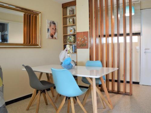 une salle à manger avec une table et des chaises bleues dans l'établissement Appartement T2 avec Terrasse Sud, Climatisé, à Proximité Plage - Le Lavandou - FR-1-251-295, au Lavandou