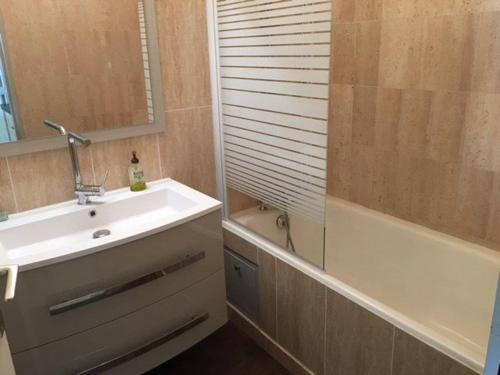 une salle de bain avec un lavabo, une baignoire et un miroir dans l'établissement Charmant 2P en bord de mer, 4 couchages, marina, proche gare et centre, parking vélos et scooters - FR-1-252A-9, à Villeneuve-Loubet