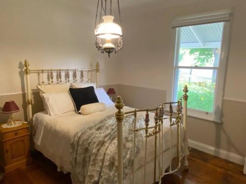 Schlafzimmer mit einem Bett, einem Fenster und einem Kronleuchter in der Unterkunft Glendale Cottage in Daylesford