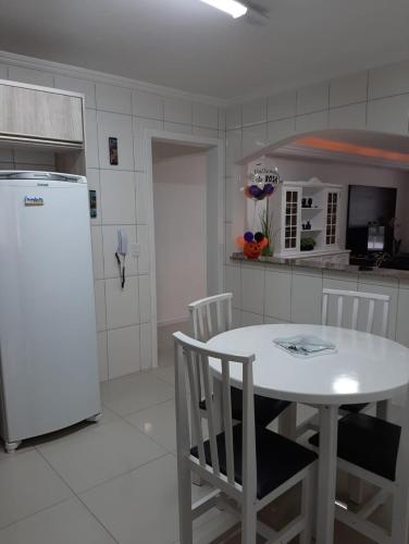 cocina con mesa blanca y nevera blanca en Meia Praia - apartamento com sacada ampla e churrasqueira, próximo a praia e a avenida principal., en Itapema