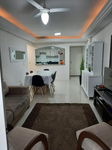 sala de estar con mesa y sofá en Meia Praia - apartamento com sacada ampla e churrasqueira, próximo a praia e a avenida principal., en Itapema