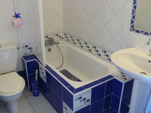 La salle de bains est pourvue d'une baignoire bleue et blanche ainsi que d'un lavabo. dans l'établissement Appartement 2 étoiles avec piscine, balcon, 2 chambres, proche plage - Le Lavandou - FR-1-308-92, au Lavandou