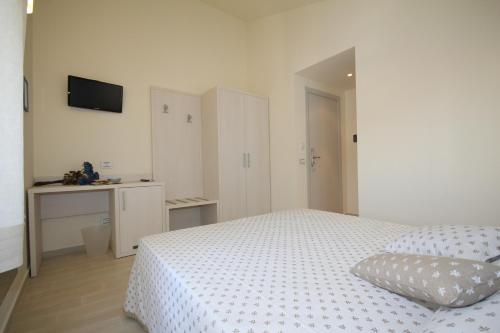 Habitación blanca con cama y escritorio en Affittacamere le Tre Sorelle, en Sirolo