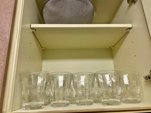 a row of empty glasses sitting on a shelf at Hotel EL 8（宇都宮駅東口） in Utsunomiya