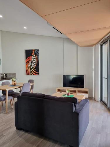 a living room with a couch and a tv at Waverley apartment D-one bedroom wifi available in Perth