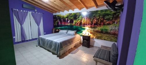1 dormitorio con 1 cama y una pintura en la pared en La Chelca en San Fernando del Valle de Catamarca