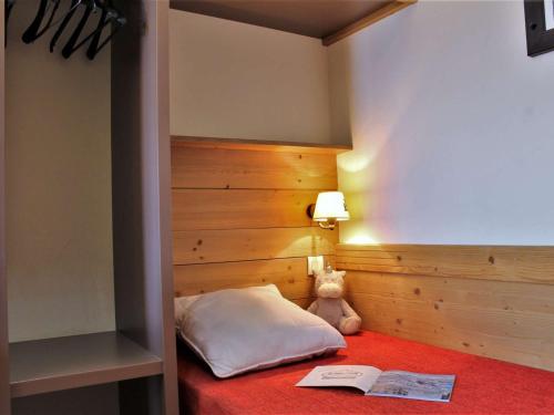 a teddy bear sitting on a bed with a book at Appartement Risoul, 2 pièces, 5 personnes - FR-1-330-446 in Risoul