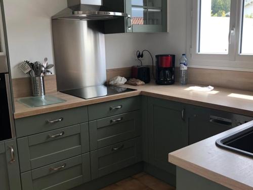 une cuisine avec des placards verts et un comptoir dans l'établissement Maison Neuve à La Couarde: Proche Centre, Plages et Marché, Jardin et Terrasse équipés - FR-1-434-35, à La Couarde-sur-Mer